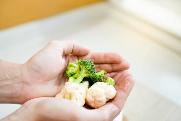 Close up view and selective focus of broccoli and cauliflower vegetables being held by open hands