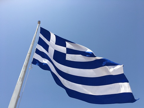 A blue and white flag of Greece waves in the wind