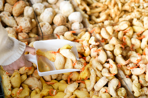 Close up view of people choosing raw or undone tempura shrimp, breaded, crispy, deep fried in batter.