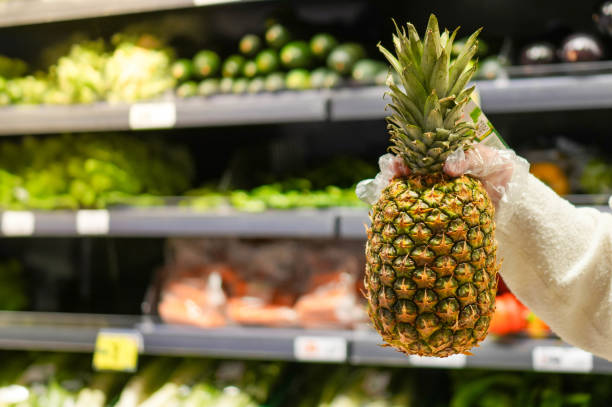 Female hand taking and showing a pineapple to camera with copy space