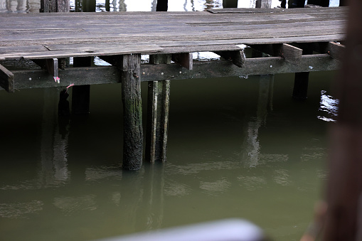 Wooden pier on the river with water reflection in the water.