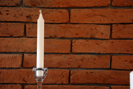 Candle on a brick wall background. Candlelight in a glass candlestick.