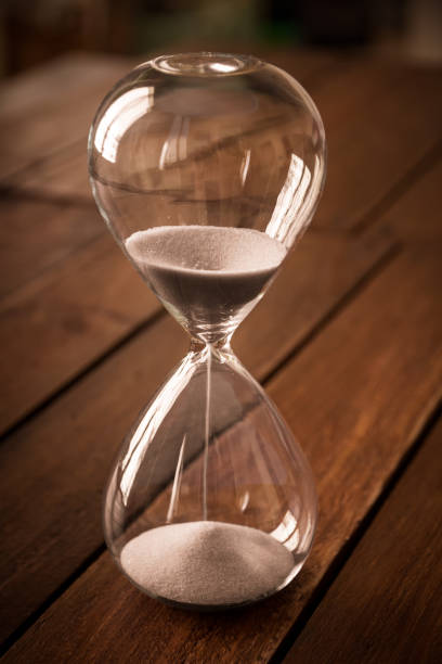 istock Hourglass containing white sand on a rustic wooden board 1816033321