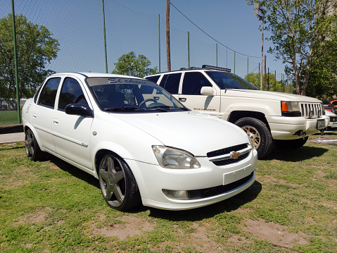 Remedios de Escalada, Argentina - Oct 8, 2023: White 2010s Chevrolet Classic four door sedan on the lawn at a car show in a park. Sunny day