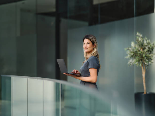 istock Smiling businesswoman using laptop in a hallway. 1816056635