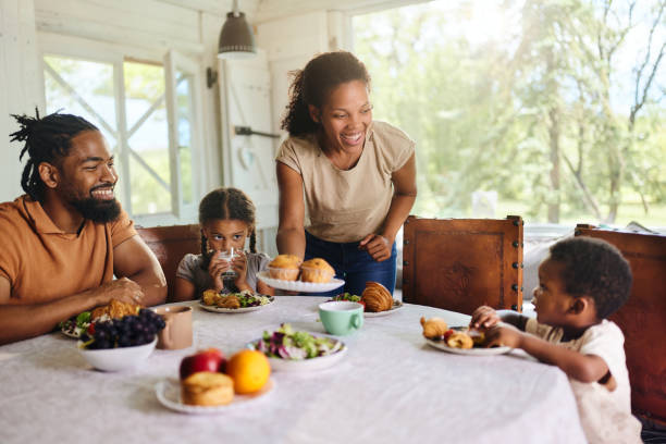 Happy black family talking during breakfast at dining table.