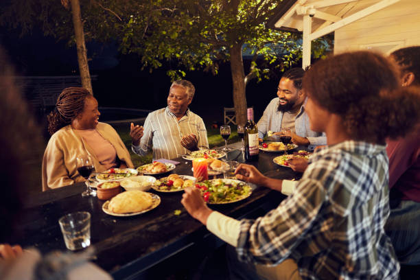istock Happy black multi-generation family talking on dinner at picnic table by night. 1816075751
