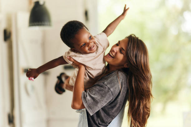 Happy single mother having fun with her adopted black son at home. Happy single mother having fun with her adopted African American son at home. mother stock pictures, royalty-free photos & images