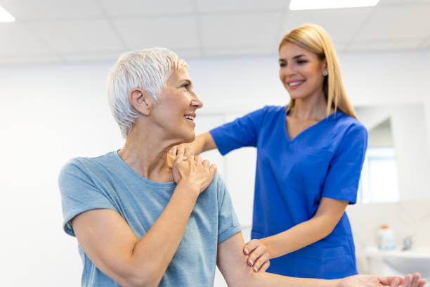 istock Happy senior woman doing exercise with physiotherapist. Old retired lady doing stretching arms at clinic with the help of a personal trainer during a rehabilitation session. 1816082235