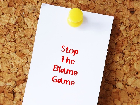 White note paper pin on office cork board background with handwriting STOP THE BLAME GAME, to avoid situation when people attempt to blame each other when bad things has happened