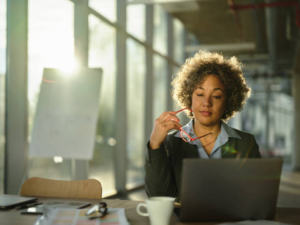 zamyślona bizneswoman pracująca na laptopie w biurze. - pensive women business mature adult zdjęcia i obrazy z banku zdjęć