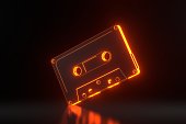 Vintage audio tape cassette with bright glowing futuristic orange neon lights on a black background
