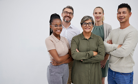 Confident diverse businesspeople standing with arms crossed against a grey background. Multiethnic colleagues looking proud and determined to achieve success with teamwork, collaboration and unity