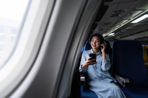 istock Asian people female person onboard, airplane window, using mobile and headphone while on the plane 1816132863