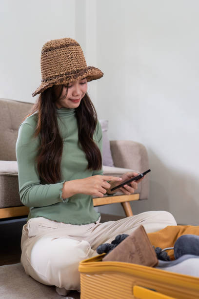 mulher feliz usando o smartphone reservando férias na agência de viagens ou fazendo reserva de hotel on-line - national cash register - fotografias e filmes do acervo