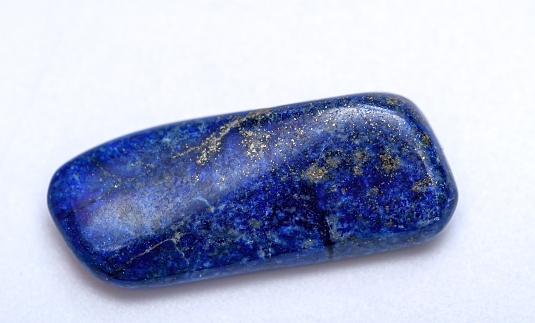 Close-up cut lapis lazuli gemstone, beautiful navy blue piece, isolated