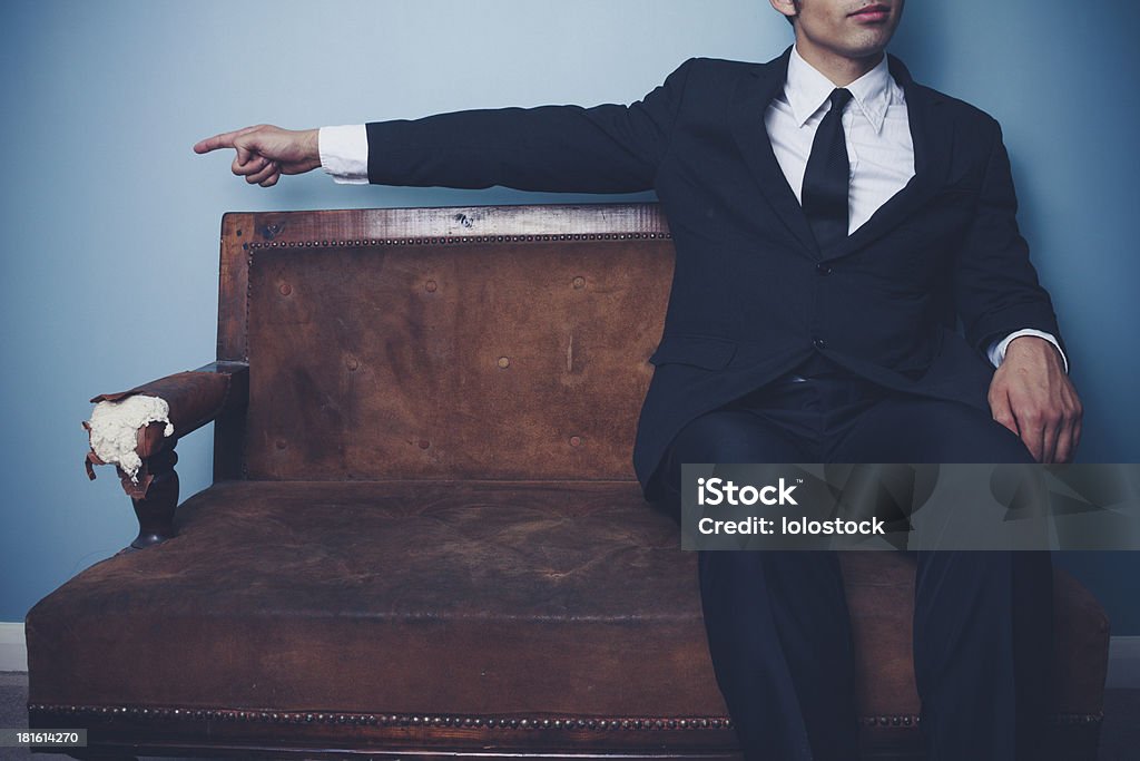 Uomo d'affari sul divano che punta a sinistra - Foto stock royalty-free di Divano