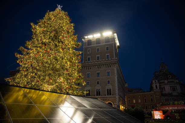 Rome, Italy - December 25, 2022: Christmas tree in Piazza Venezia, with Christmas decorations and lights, in front of the National Monument Altare della Patria on December 25, 2022 in Rome, Italy. The tree is powered by solar panels sustainable energy