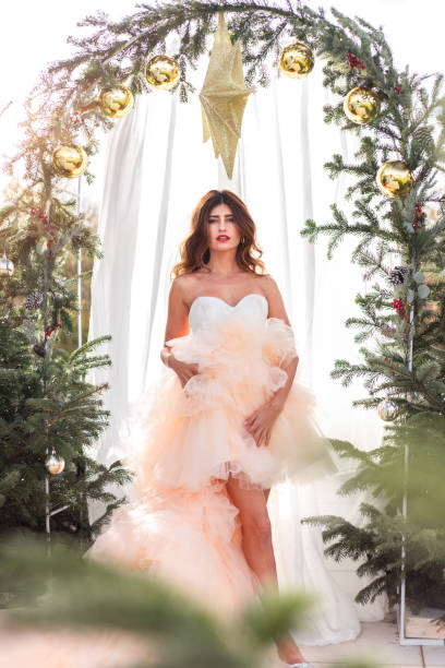 femme avec noël en robe élégante dans la mariée lumineuse de scène d’arbre de noël d’arbre de noël dans la lumière chaude du soleil pour le mariage de décembre - christmas wedding bride winter photos et images de collection