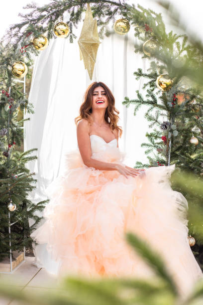 femme avec noël en robe élégante dans la mariée lumineuse de scène d’arbre de noël d’arbre de noël dans la lumière chaude du soleil pour le mariage de décembre - christmas wedding bride winter photos et images de collection