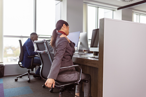 Office worker doing stretching exercises while on her work place behind the computer