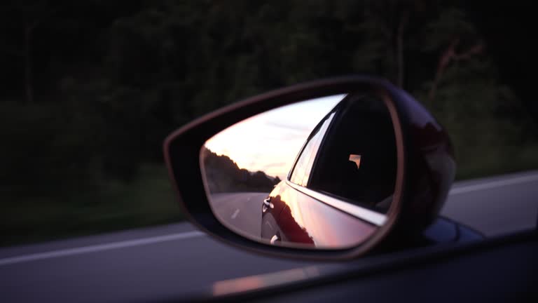 Reflection of road side rear-view mirror on car.
sunset in the side mirror of the red car.