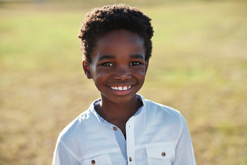 Portrait little african american boy smiling looking happy on summer day in park