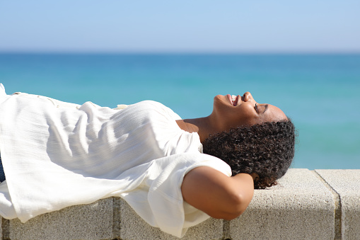 Happy black woman lying on the beach