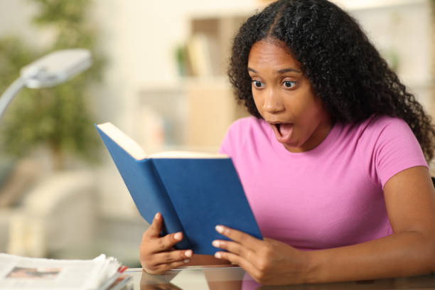 istock Amazed black woman reading a book at home 1816190737