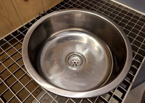 Photo of the stainless steel sink embedded in  grid resembles the interior of an airplane. however, it is on the bike path by the public toilets. truck, pub, football, camp, prison, prison, gas station, circle