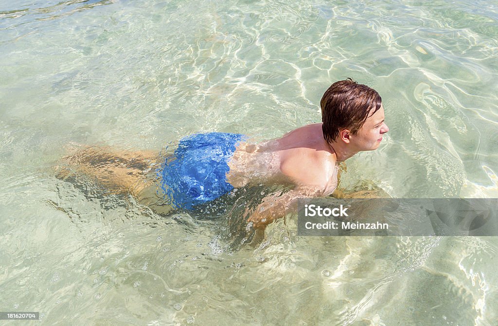 Przystojny nastolatka ma zabawy w basenie z widokiem na ocean - Zbiór zdjęć royalty-free (Chłopcy)