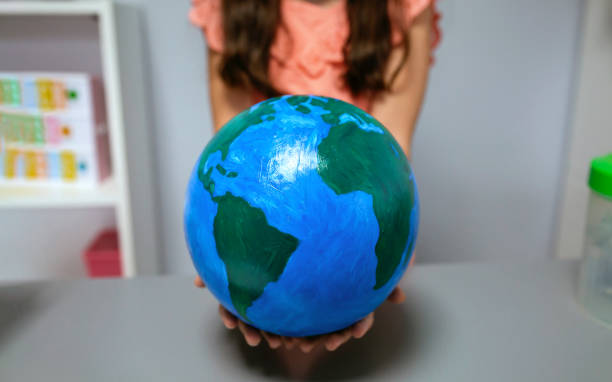 istock Unrecognizable female student showing a handmade globe world at ecology classroom 1816215154