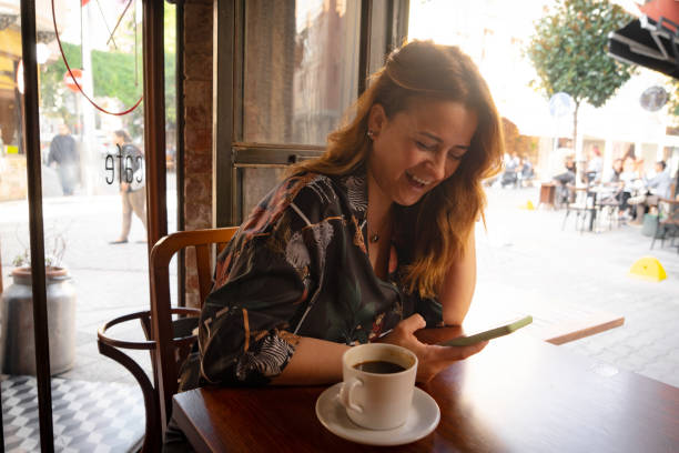 istock Happy young woman using mobile phone and enjoying coffee at cafe 1816227924