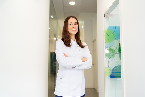 Happy beauty dentist standing with arms crossed in the clinic