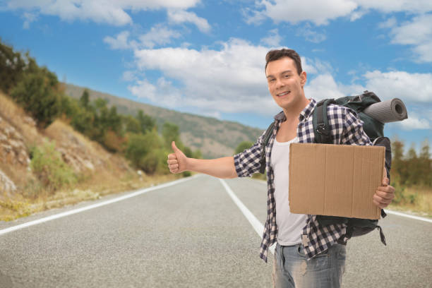 Male hitchhiker holding a cardboard sign on the road
