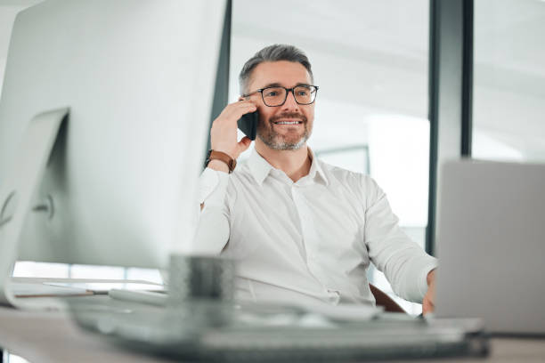 istock Mature business man, phone call and computer for networking, consulting and communication of news in office. Happy entrepreneur, mobile conversation and chat for negotiation, offer or talk to contact 1816261023