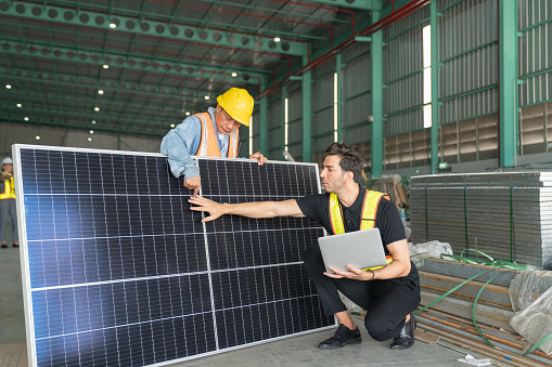 Worker and engineer checking solar panel in warehouse. This is a freight transportation and distribution warehouse.