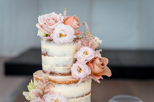 Multilevel wedding cake on the table decorated with roses.