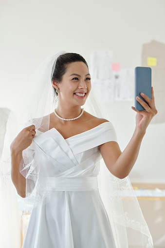 Portrait of happy bride taking selfie or filming video for social media