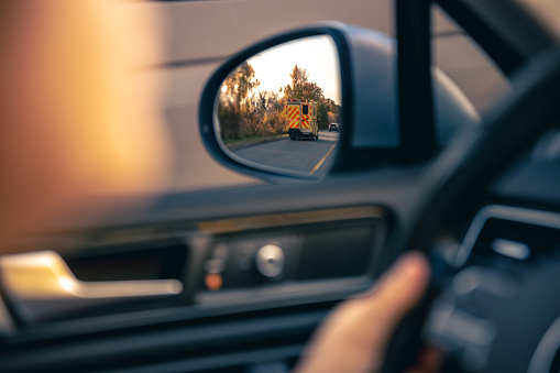 The view of the road in the car's rearview mirror, travel by personal car.