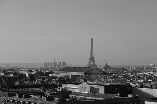 A long distance view of the Eiffel Towel. Taken on the rooftop of Galerie Lafayette, with rooftop view of Paris.  Also in the background is La Defense.