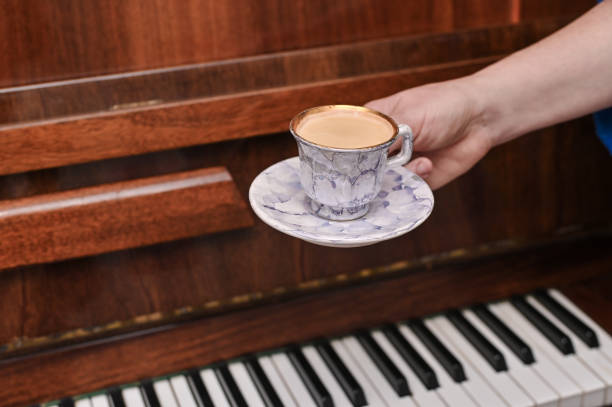 uma xícara de café na mão no fundo de um velho teclado de piano. conceito - espresso music theatrical performance coffee - fotografias e filmes do acervo
