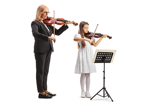 Girl practicing violin with a female teacher isolated on white background