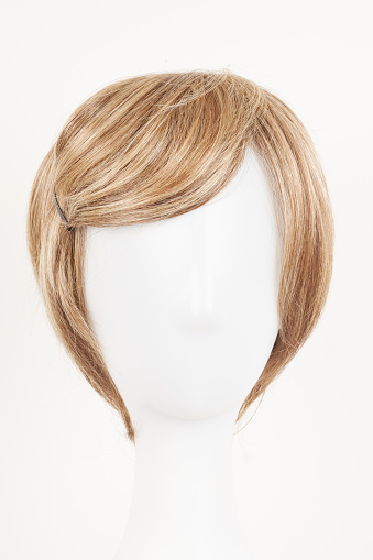 Natural looking blonde fair wig on white mannequin head. Short hair cut on the plastic wig holder isolated on white background, front view