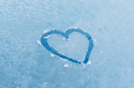 heart symbol on frozen window in winter