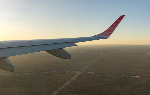 Wing of a plane over a crossroad in the country, aerial