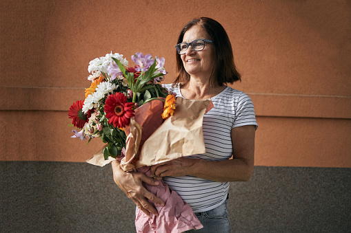 Senior woman is holding flower arrangement on mother’s day.