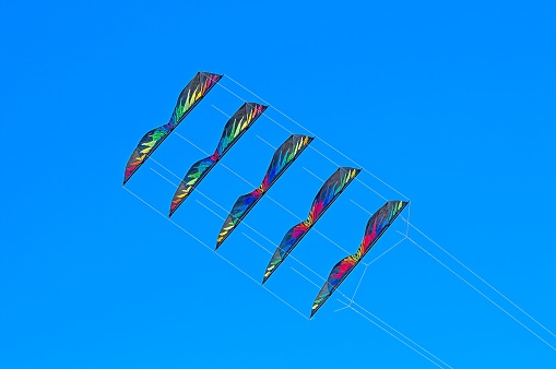 Multi-coloured Stacked Stunt Kites flying in a Clear Blue Sky