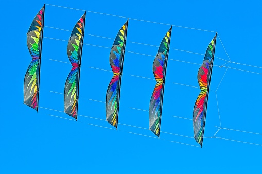 Multi-coloured Stacked Stunt Kites flying in a Clear Blue Sk