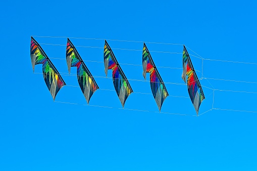 Multi-coloured Stacked Stunt Kites flying in a Clear Blue Sk